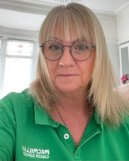 Woman with blonde hair and glasses wearing a green polo shirt