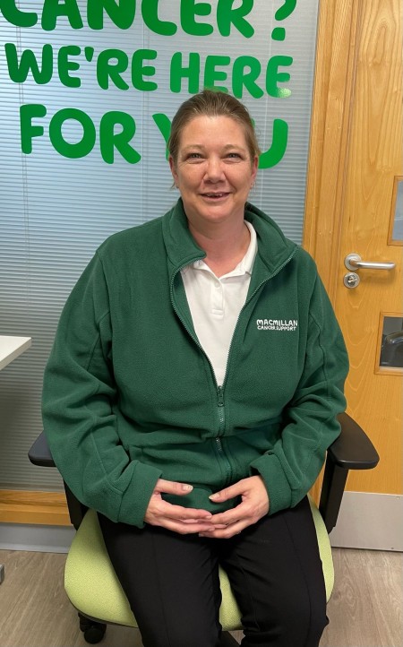 Woman with dark hair wearing a white polo shirt and a green fleece top