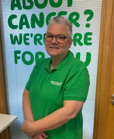 Woman with short grey hair, wearing glasses and wearing a green polo shirt